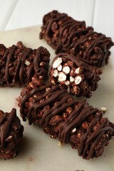 Delicious chocolate puffed rice bars on white wooden table, closeup