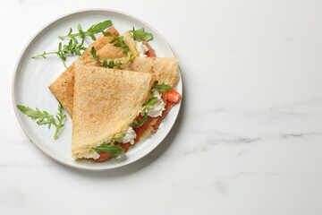 Delicious crepes with salmon, cream cheese and arugula on white marble table, top view. Space for text