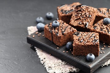 Delicious chocolate puffed rice bars and blueberries on gray textured table, closeup. Space for text