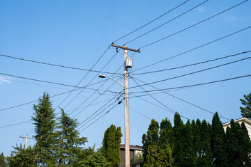 Mess of overhead power lines in a residential neighborhood, wood utility pole and transformer,...
