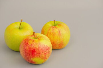Three apples on a gray background.