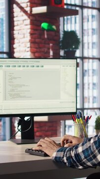 Programmer at desk typing code into computer, developing software programs, consulting green screen tablet. Man in home office fixing errors in application using chroma key device and PC, camera A