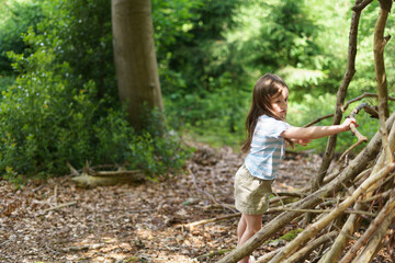 Little girl in hat walks in forest in summer. Concept of healthy child's games in open air