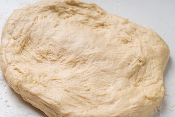 Yeast dough for a pie or pizza on a white table with flour. Pizza cooking process, recipe
