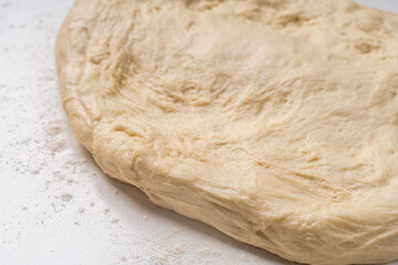 Yeast dough for a pie or pizza on a white table with flour. Pizza cooking process, recipe