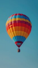 Obraz premium A vibrant hot air balloon soaring against a clear blue sky.