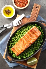 Delicious grilled salmon fillet in baking dish served on grey textured table, flat lay