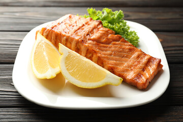 Delicious grilled salmon fillet served on wooden table, closeup