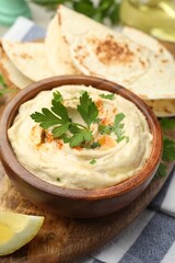 Delicious hummus with parsley, paprika and pita on table, closeup