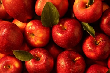 Fresh ripe red apples and green leaves as background, closeup