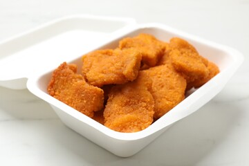 Tasty chicken nuggets on white marble table, closeup