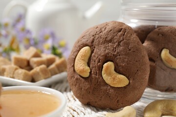Tasty chocolate cookies with cashew on wicker mat, closeup