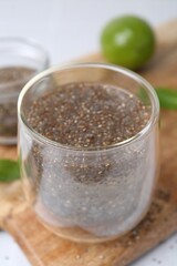 Glass of drink with chia seeds and lime on white table, closeup