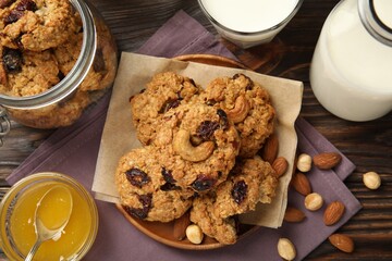 Delicious oatmeal cookies with raisins and nuts served on wooden table, flat lay