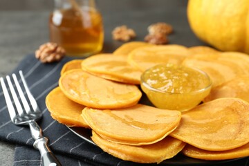 Tasty pumpkin pancakes with honey and jam on table, closeup