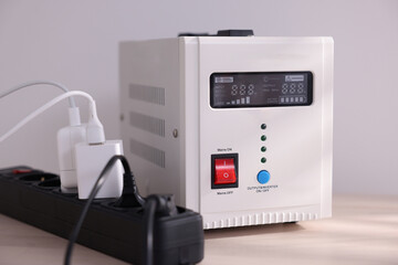 Portable power station and multi-socket extension board with chargers on table indoors, closeup