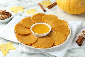 Tasty pumpkin pancakes on white marble table, closeup