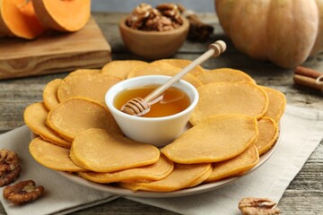 Tasty pumpkin pancakes, honey and walnuts on wooden table, closeup