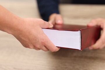 Writer signing book for reader at wooden table, closeup