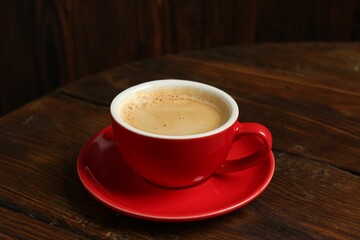 Red cup with coffee on wooden table
