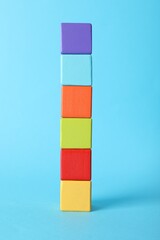 Colorful wooden cubes on light blue background