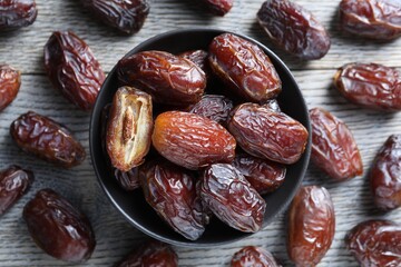Tasty dried dates on light wooden table, flat lay