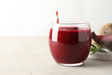 Fresh beetroot smoothie in glass on grey textured table, closeup. Space for text