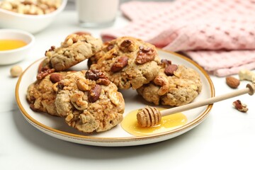Tasty cookies with nuts and honey dipper on white table, closeup