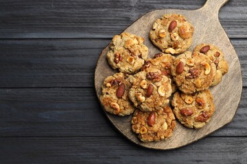 Tasty cookies with nuts on dark wooden table, top view. Space for text
