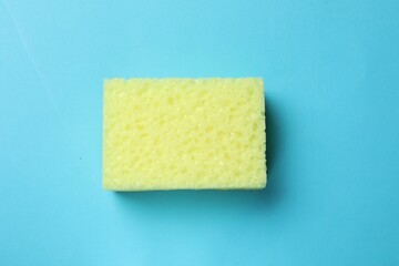 Soft sponge on light blue background, top view. Cleaning tool