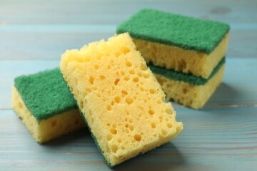Soft sponges on light blue wooden table, closeup