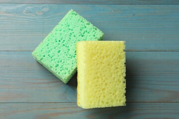 Soft sponges on light blue wooden table, top view
