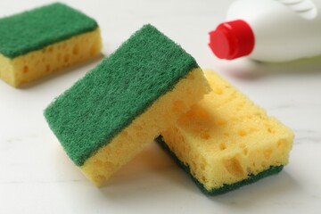 Soft sponges and dish soap on white table, closeup