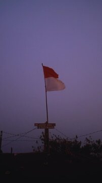 The flag of Indonesia at the peak of the Batur volcano. The top of a mountain in Bali. Adventures in Asia, hiking in the mountains.