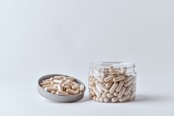Clear supplement capsules filled with beige powder in clear pet jar pharmaceutical concept