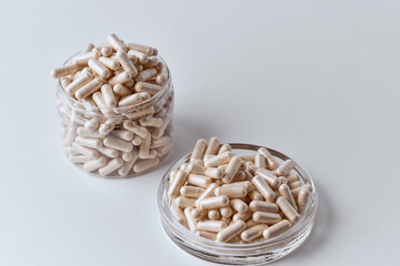 Clear capsules filled with beige powder in clear PET jar and petri dish pharmaceutical concept