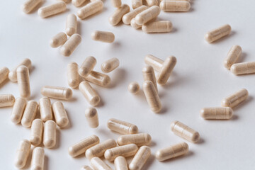 Clear capsules filled with beige powder spilled on white background pharmaceutical concept