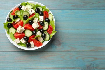 Delicious salad with feta cheese on light blue wooden table, top view. Space for text