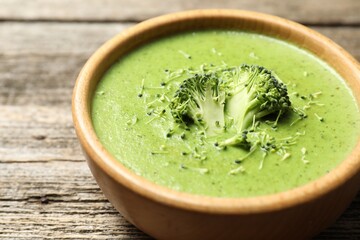 Delicious broccoli cream soup in bowl on wooden table, closeup