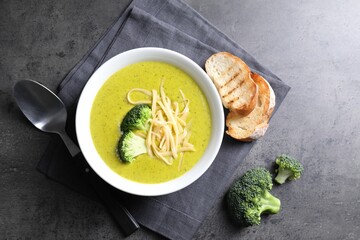 Delicious broccoli cream soup served on gray textured table, flat lay