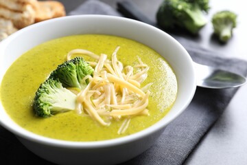 Delicious broccoli cream soup served on gray table, closeup