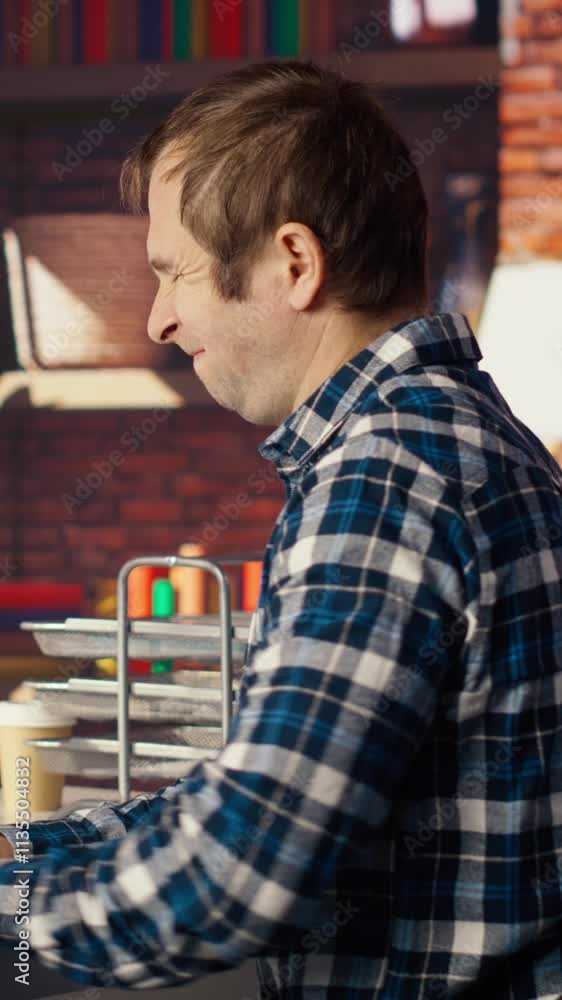 Fototapete man in home office stretches back while looking at ui on pc screen, feeling fatigued while executing