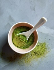 Spoonful of vibrant green matcha powder in a bowl.