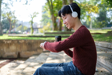 Young man drinking coffee and checking his smartwatch while sitting on outdoor stone steps.