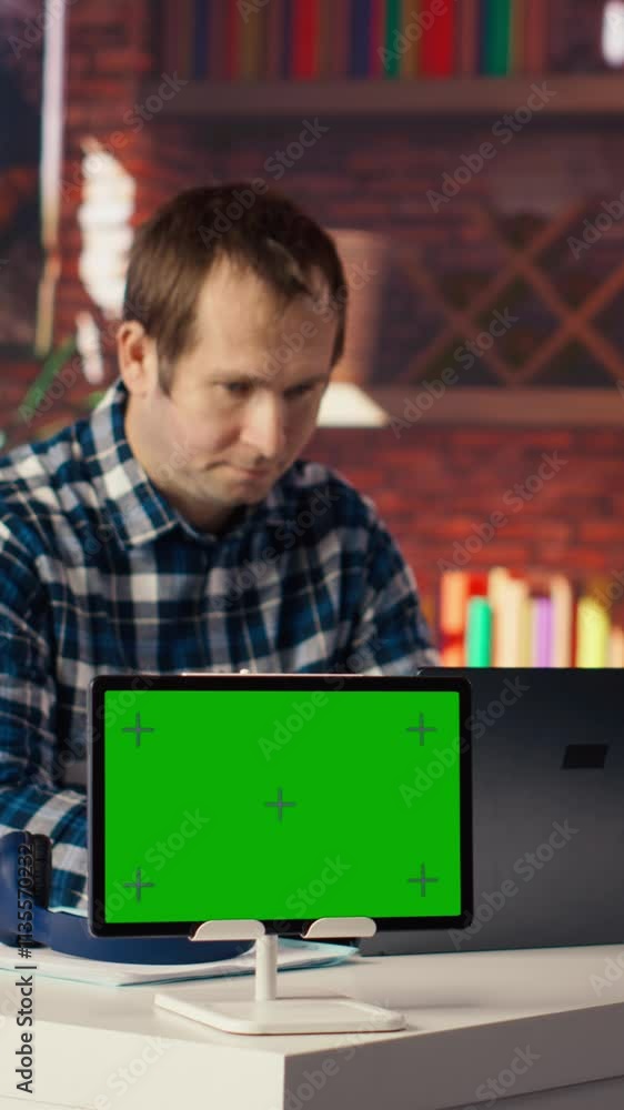 Poster mockup tablet next to worker listening music, analyzing data on laptop at desk, compiling reports. i