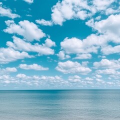 Fototapeta premium Calm ocean scene with blue sky and fluffy white clouds.