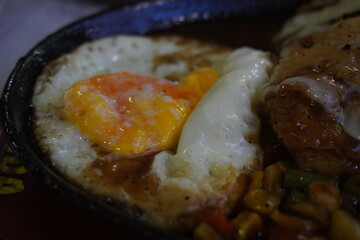 Sunnyside up eggs on a hotplate with noodles