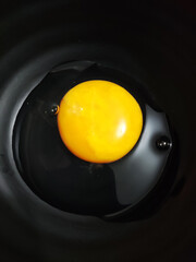 Bright yellow raw eggs placed on top of a black bowl