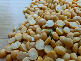 Small yellow split peas on wooden surface close up