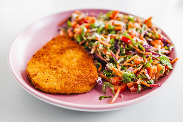 plant-based schnitzel cutlet next to kaleslaw salad